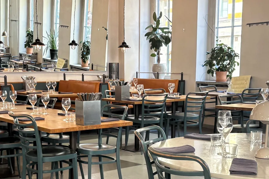Den mindre delen med uppdukade bord, orange läderbänkar och speglar längs väggen mot höga fönster